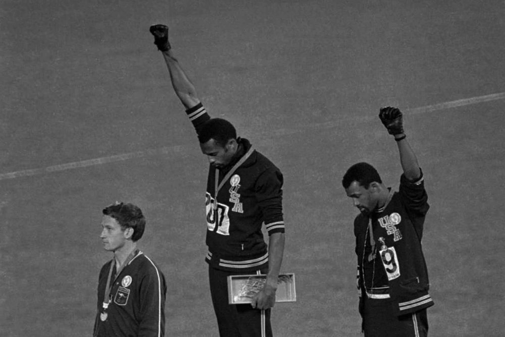 Extending gloved hands skyward in racial protest, U.S. athletes Tommie Smith, center, and John Carlos stare downward during the playing of &quot;The Star-Spangled Banner&quot; after Smith received the gold and Carlos the bronze for the 200-meter run at the Summer Olympic Games in Mexico City on Oct. 16, 1968. (AP)