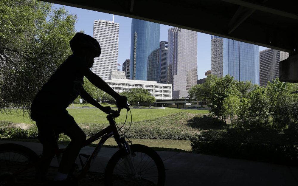 A young boy rides his bicycle along Houston's Buffalo Bayou as it snakes its way into downtown below a highway overpass, Friday, April 18, 2014. (Pat Sullivan/AP)