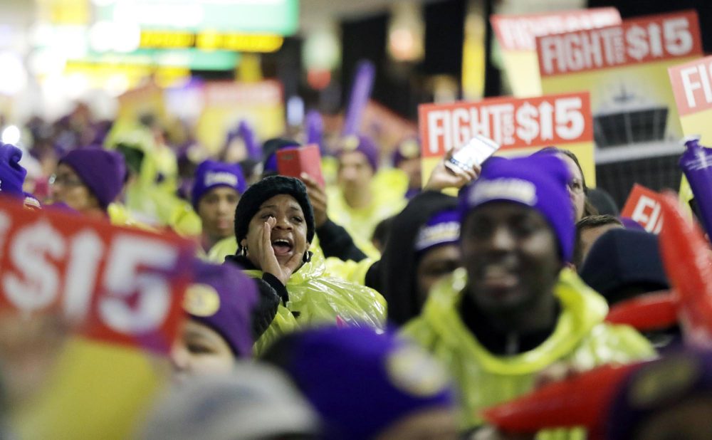 A woman shouts while marching with service workers asking for $15 minimum wage pay during a rally at Newark Liberty International Airport in New Jersey in 2016. (Julio Cortez/AP)