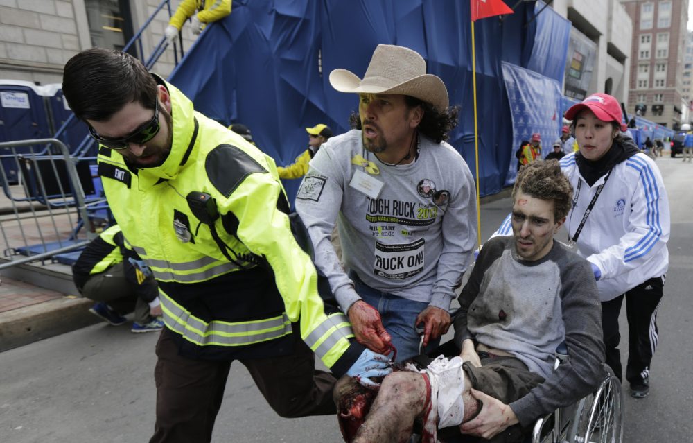 Jeff Bauman is wheeled away from the bombing on April 15, 2013 by EMT Paul Mitchell, Carlos Arredondo and Devin Wang. (Charles Krupa/AP)