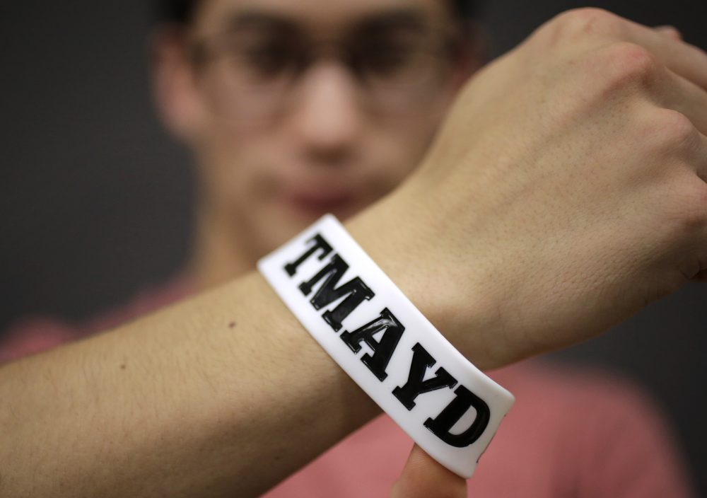 In this Feb. 1, 2016 photo, Massachusetts Institute of Technology student Andy Trattner displays a wrist band that features the acronym TMAYD for "Tell Me About Your Day," a campaign to encourage students to talk to one another in an effort to defuse to the stress of campus life before it leads to a crisis. (Steven Senne/AP)