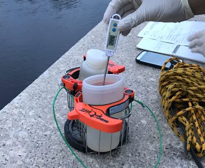 Water quality testing is done by volunteers on a recent morning on the Eliot Bridge in Boston. (Sam Turken for WBUR)