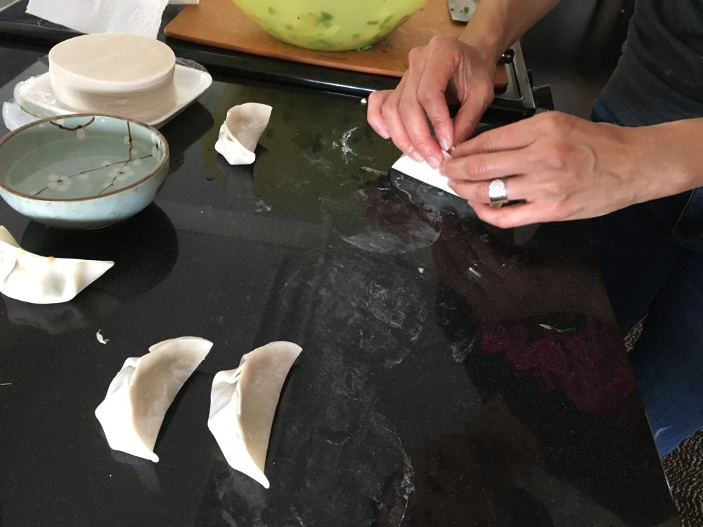 Joanne Chang demonstrates how her mother pleats dumplings. (Meghna Chakrabarti/WBUR)