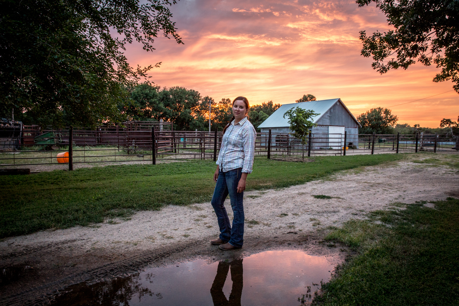 After completing her nightly chores, Meghan Hammond pauses briefly under a brilliant July sunset before heading back home to her farm in Lushton, Nebraska. (Ted Genoways)