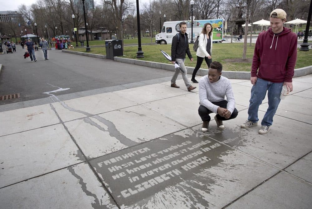 Mayor's Mural Crew staff Jerome Jones and Connor Woods look over a poem they placed on the sidewalk near Park Street station in April 2016. (Robin Lubbock/WBUR)
