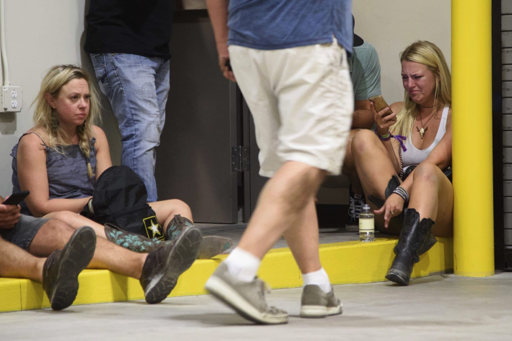 A young woman checks her phone while hiding inside the Sands Corporation plane hangar. (Al Powers/Invision/AP)