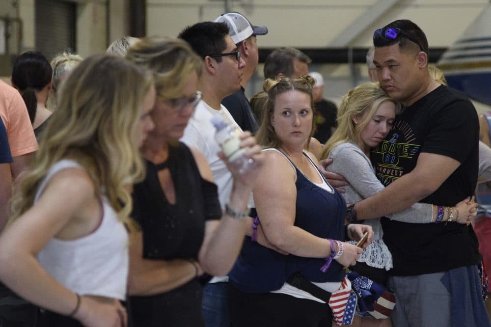 Concertgoers embrace as they wait early Monday inside the Sands Corporation plane hangar. (Al Powers/Invision/AP)