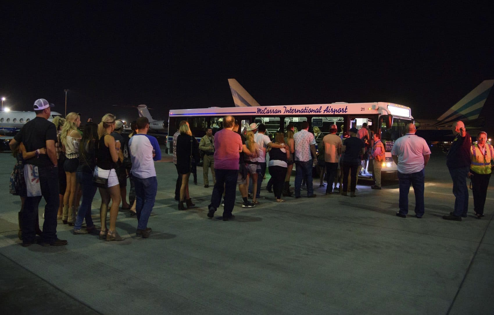 Police escort people to an evacuation bus after hiding inside the Sands Corporation plane hangar. (Al Powers/Invision/AP)
