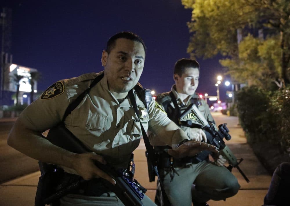 Police officers advise people to take cover near the scene of a shooting on the Las Vegas Strip Sunday night. (John Locher/AP)
