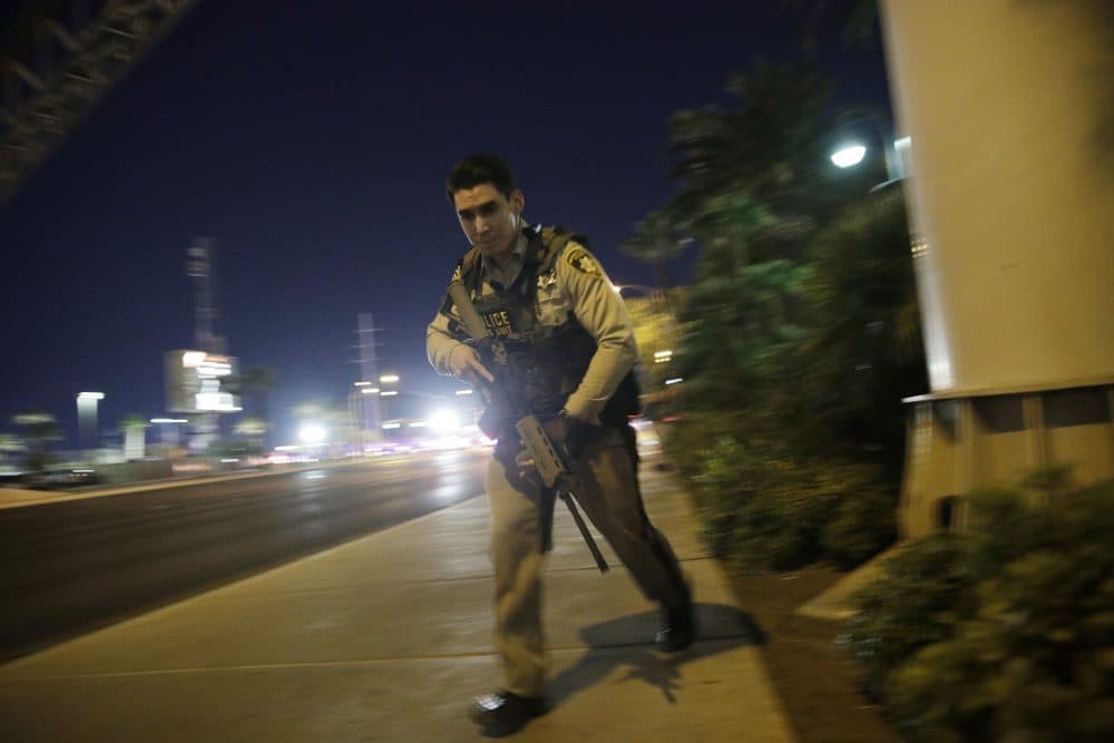 A police officer runs along a sidewalk near the shooting Sunday night. (John Locher/AP)