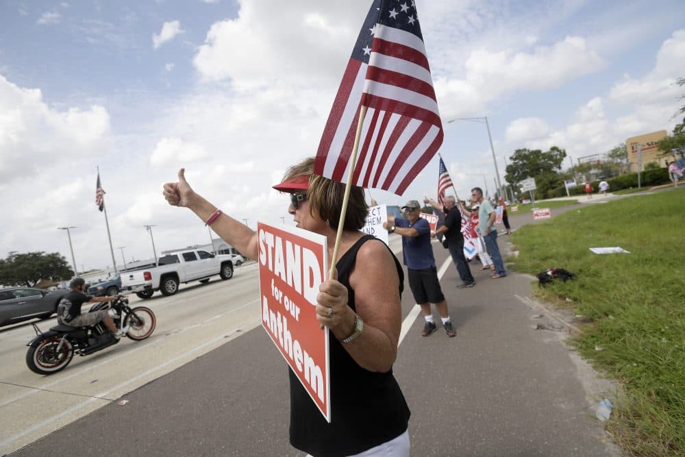 Pam Overton, of Sarasota, Fla., protests with others upset with players kneeling during the national anthem stand along a road leading to Raymond James Stadium before an NFL football game between the Tampa Bay Buccaneers and the New York Giants Sunday, Oct. 1, 2017, in Tampa, Fla. (Phelan M. Ebenhack/AP)