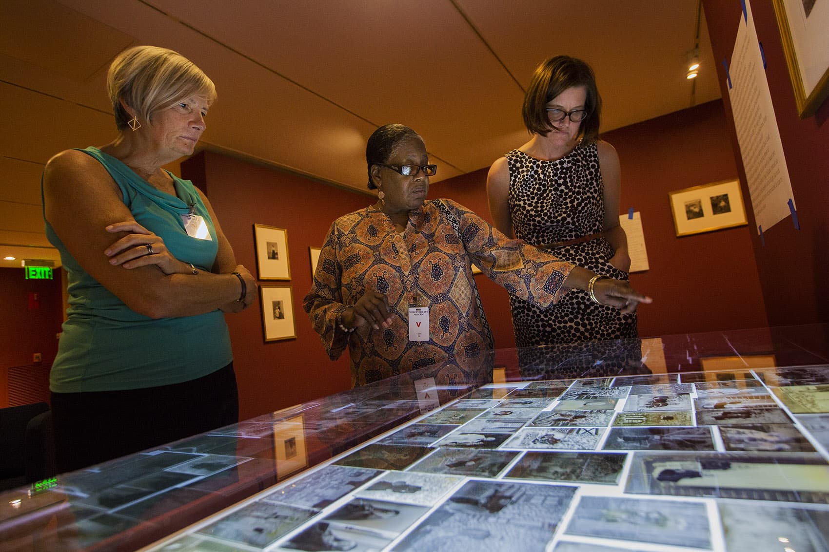 Clark Professor Janette Greenwood, Benetta Kuffour and curator Nancy Burns look at the negatives. (Jesse Costa/WBUR)