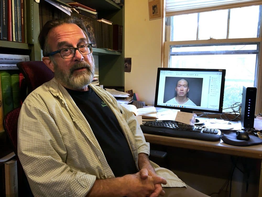 Greg Gibson, with a photo of his son's killer, Wayne Lo, on a computer screen (Anthony Brooks/WBUR)