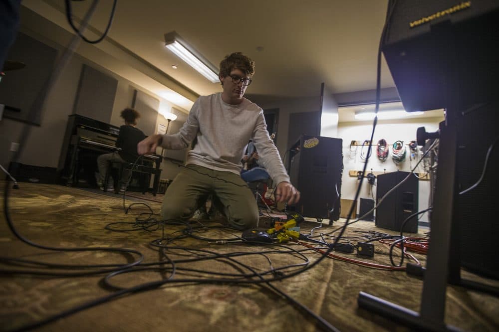 Wes Kaplan works on guitar pedals so the band Detour can rehearse ahead of Yes Fest. (Jesse Costa/WBUR)