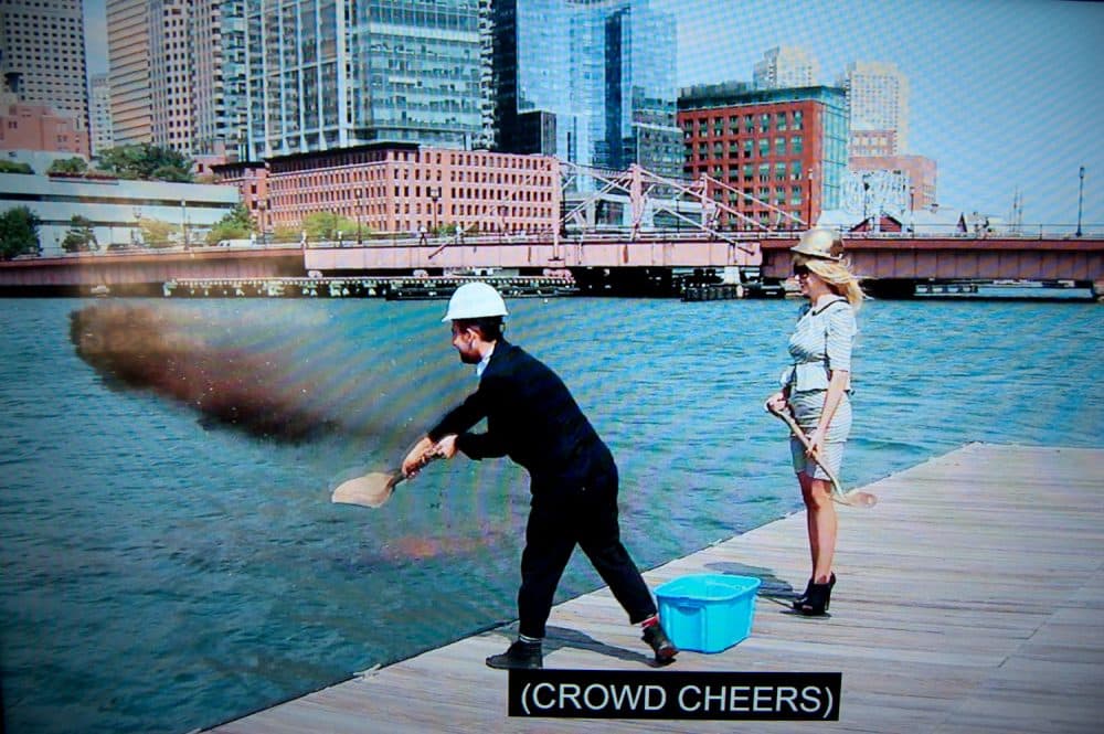 Pat Falco shovels dirt into Boston's Fort Point Channel in a video purporting to show the groundbreaking of the &quot;Luxury Waters&quot; condo tower. (Greg Cook/WBUR)