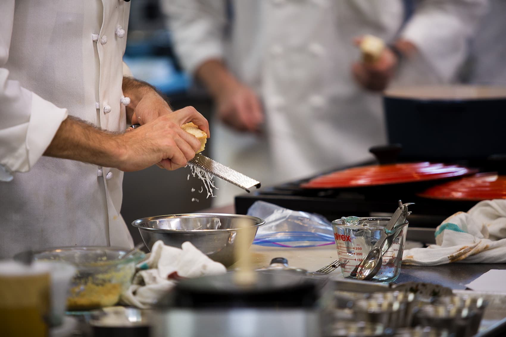 A test chef uses a microplane to grate parmesan into a bowl. (Jersse Costa/WBUR)