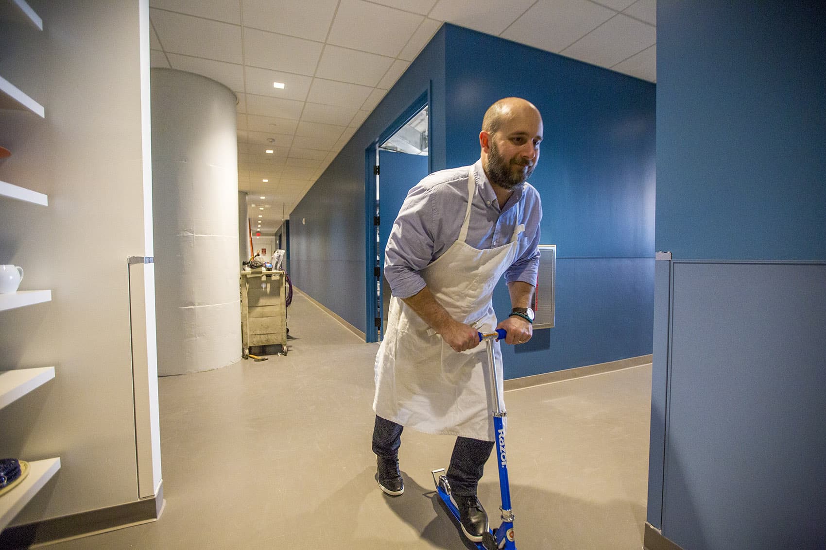 At the expansive new America's Test Kitchen in Boston's Seaport, Cook's Country editor Bryan Roof rides his Razor scooter around. (Jesse Costa/WBUR)