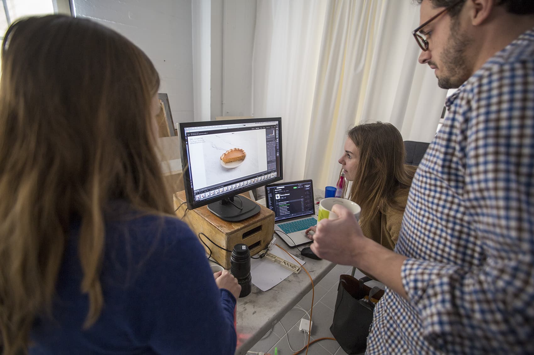 Art directors review a photo of a pumpkin pie with executive editor Dan Souza. (Jesse Costa/WBUR)