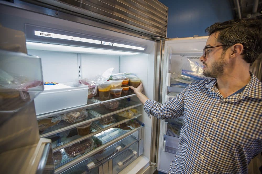 Dan Souza takes a peek in the Take Home Fridge where all leftover food from the test kitchens is placed for any employees to help promote ATK's zero waste mission. (Jesse Costa/WBUR)