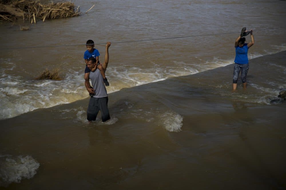 A man carries his son on his shoulders between as he wades a river in the San Lorenzo neighborhood of Morovis, Puerto Rico, Sunday, Oct. 1, 2017. Because of the strength of Hurricane Maria, the bridge that communicates the neighborhood with the town was washed away, leaving San Lorenzo partly incommunicated from the rest of the town. (Ramon Espinosa/AP)