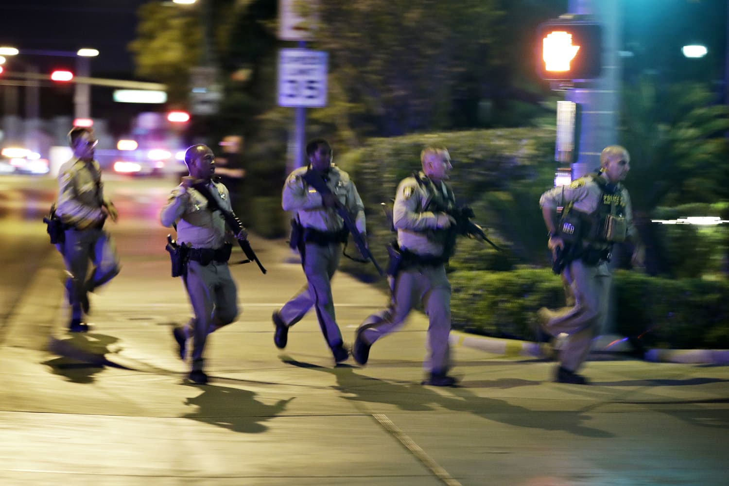Police run to cover at the scene of a shooting near the Mandalay Bay resort and casino on the Las Vegas Strip, Sunday, Oct. 1, 2017, in Las Vegas. Multiple victims were being transported to hospitals after a shooting late Sunday at a music festival on the Las Vegas Strip. (John Locher/AP)