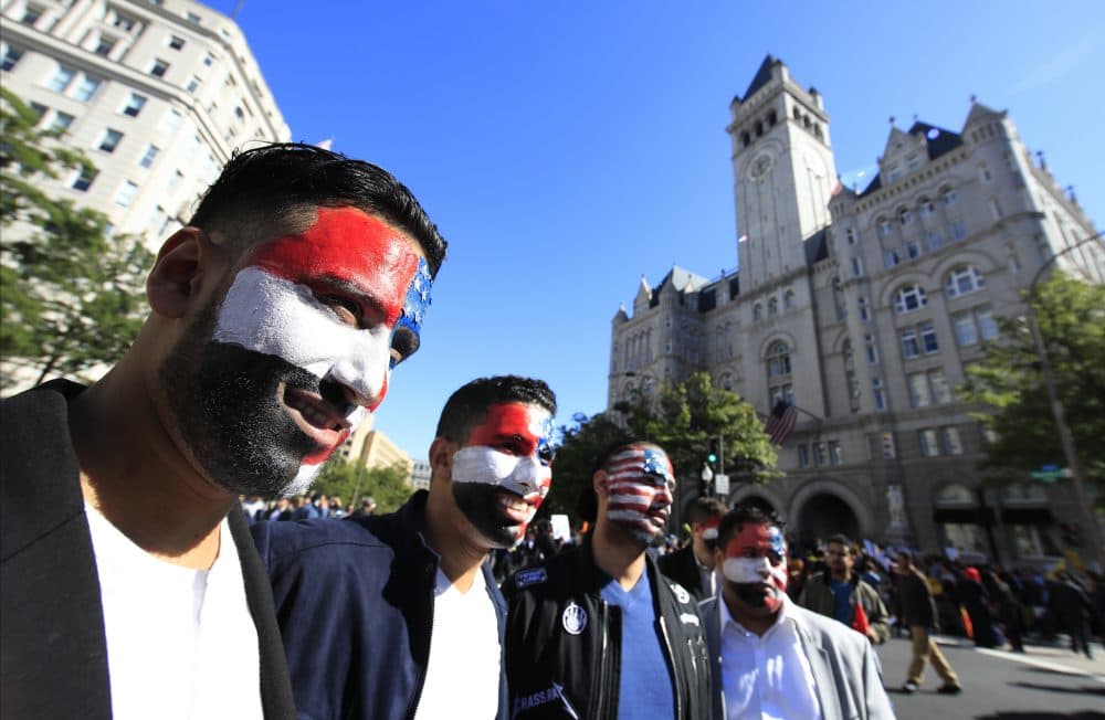Mohamed Alsaidi, left, a Yemeni descent from New York, and fellow protesters, have their face painted with the American and Yemeni colors and pose for a picture during a rally against what they call a &quot;Muslim ban&quot; in front of the Trump International Hotel in Washington on Wednesday. (Manuel Balce Ceneta/AP)