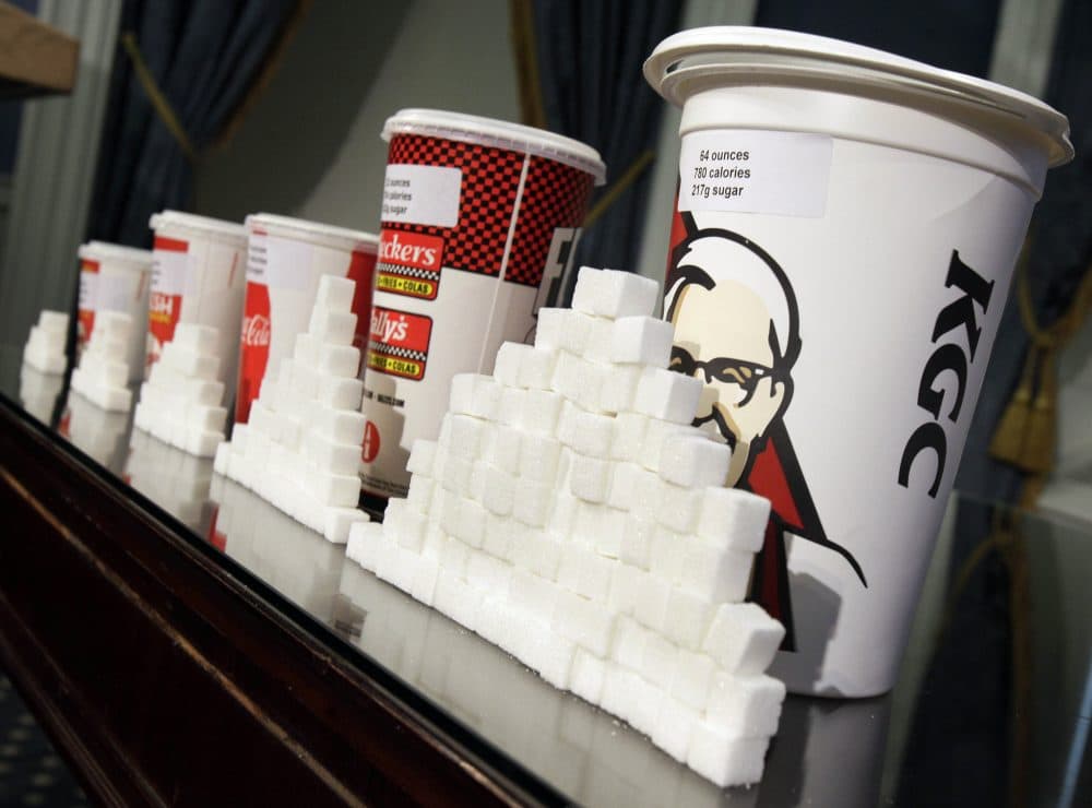 This May 31, 2012 file photo shows a display of various size soft drink cups next to stacks of sugar cubes at a news conference at New York's City Hall. (Richard Drew/AP)