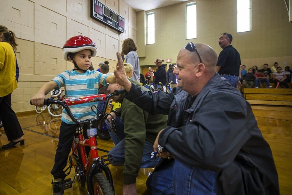 Five-year-old Christopher and Bob Charland celebrate with a high five after adjustments are made to his new bike so he can ride it. (Jesse Costa/WBUR)