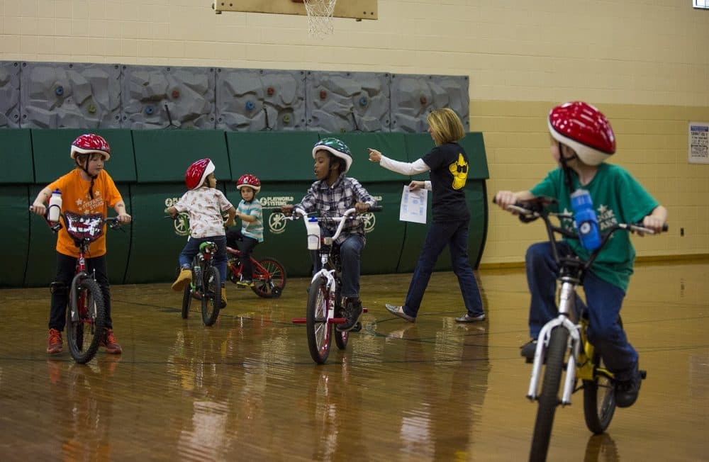 Children take test rides on their newly acquired bicycles in the gymnasium of the Stefanik School . (Jesse Costa/WBUR)