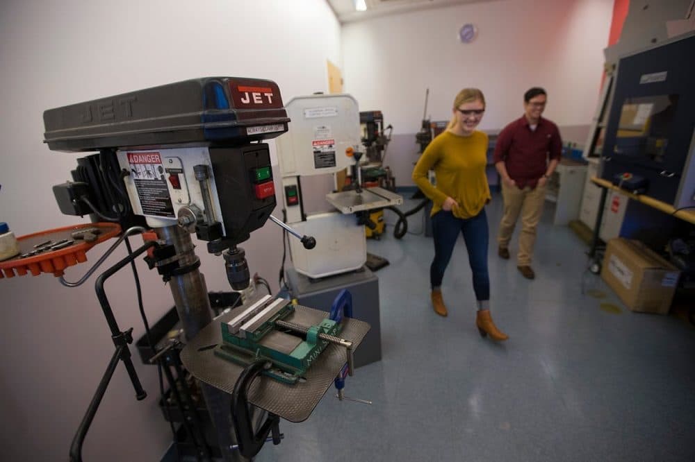 Student "Ninjas" Sara Ballantyne and Jayce Chow walk past a drill press and a band saw which are among the basic tools students are initially trained to learn in the "green room" at Olin College. (Jesse Costa/WBUR)