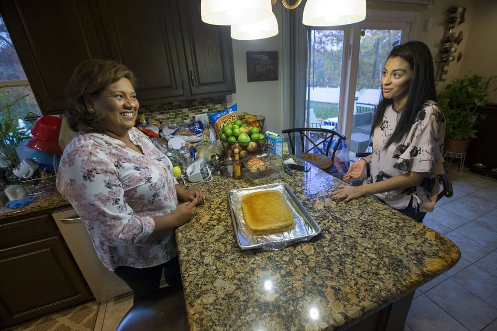 Irma Flores, right, and her daughter Gabriela Portillo-Perez discuss how to proceed with making a tres leches cake as a surprise for Portillo-Perez's husband. (Jesse Costa/WBUR)