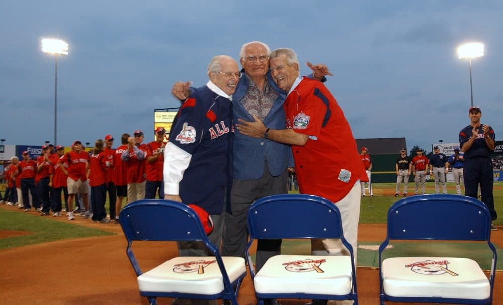 Baseball great Bobby Doer, center, hugs fellow baseball greats Dom DiMaggio, left, and Johnny Pesky as celebrity and Triple-A home run derby participants stand behind them on July 12, 2004, at McCoy Stadium in Pawtucket, R.I. (Victoria Arocho/AP)