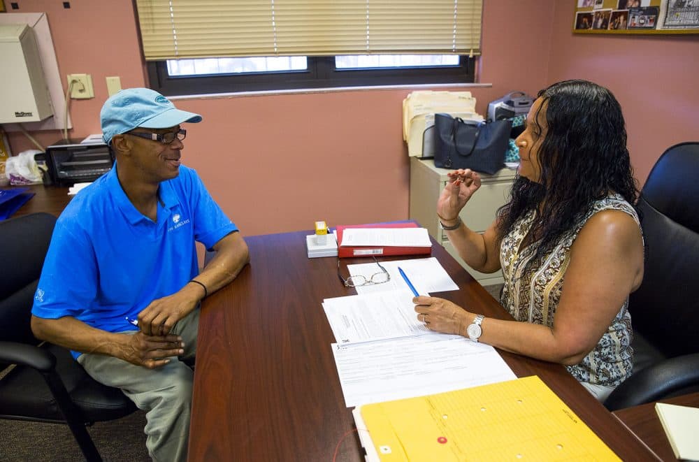 A smiling Higginbottom signs paperwork with Carmen Figueroa, the property manager. (Robin Lubbock/WBUR)