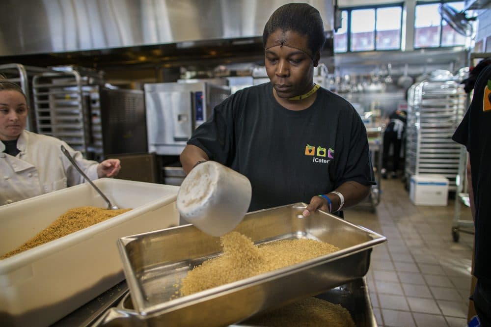 Ivanks Pipins fills a pan with dried rice. (Jesse Costa/WBUR)