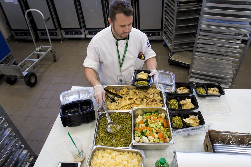 Brian Sink portions out vegetarian meals consisting of pierogies, mixed vegetables and peas. (Jesse Costa/WBUR)