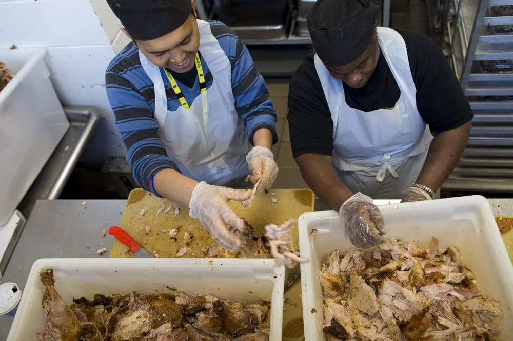 Ikegut Ginarta and India Smith separate turkey meat from the bones. (Jesse Costa/WBUR)