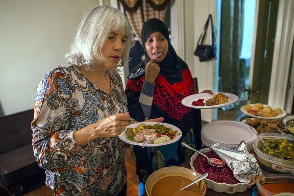 A curious Janet Amphlett listens as Hawo describes the different Somali dishes that are offered on the table. (Jesse Costa/WBUR)