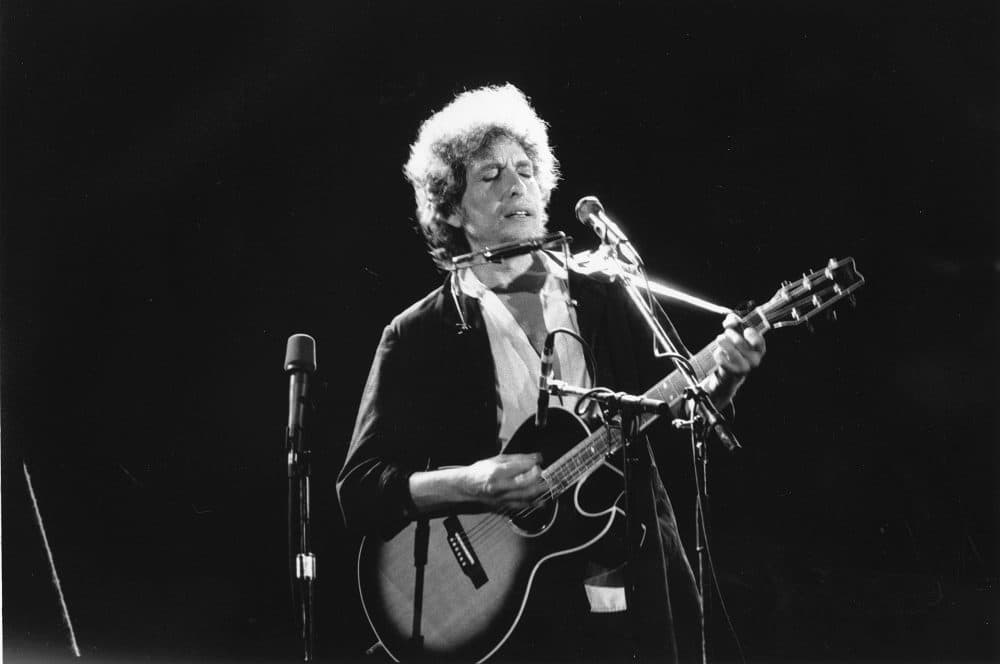 An undated photo of singer-songwriter Bob Dylan as he plays his acoustic guitar with his harmonica at an unknown location. (AP Photo)