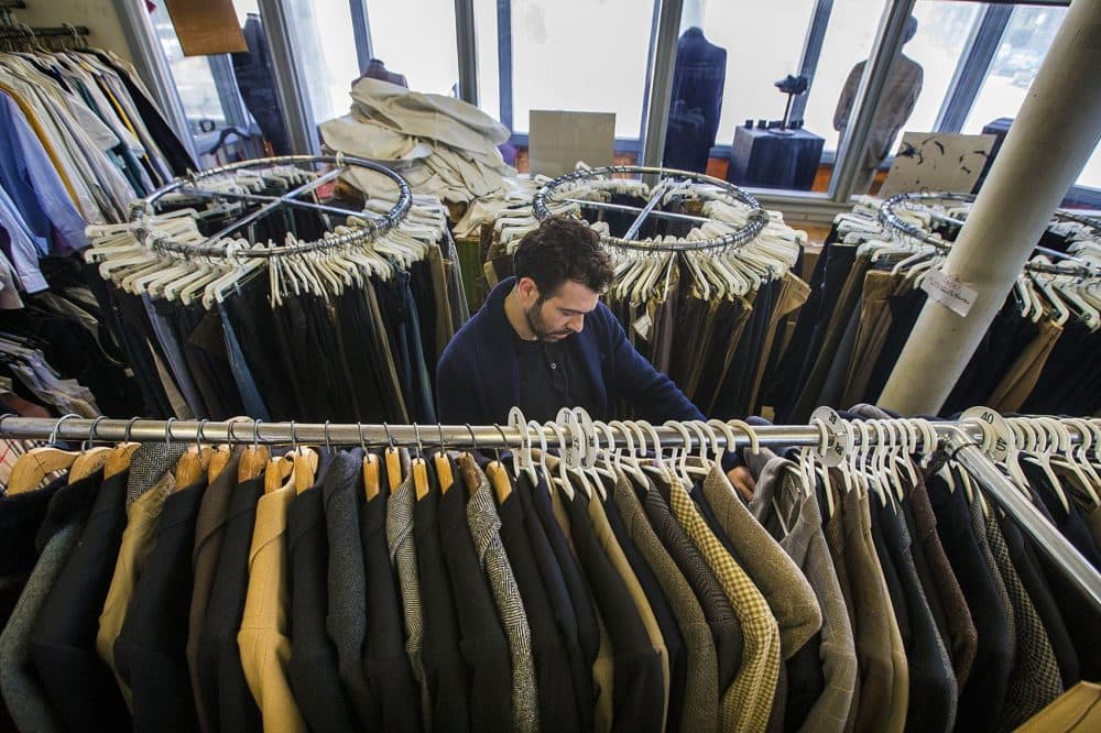 Asa Zabarsky files through a rack of suit jackets at Keezer's Classic Clothing in Cambridge. (Jesse Costa/WBUR)