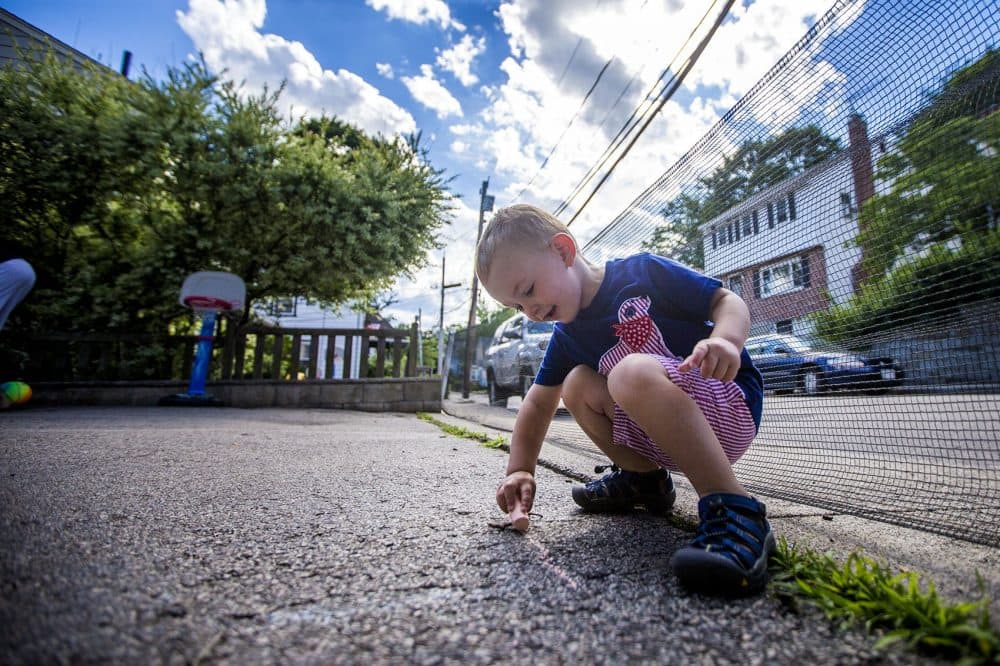 Two-and-a-half year old Robbie Klein has hemophelia, a medical condition in which the ability of the blood to clot is reduced. Using chalk Robbie is drawing the lines of the basketball court in his family's driveway preparing to play basketball. (Jesse Costa/WBUR)