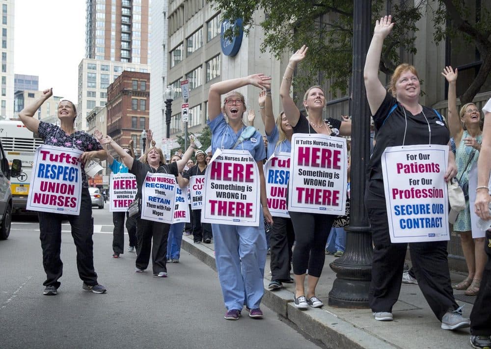 Nursing strike supporters on Washington St. wave a people inside the Tufts Medical Center. (Robin Lubbock/WBUR)