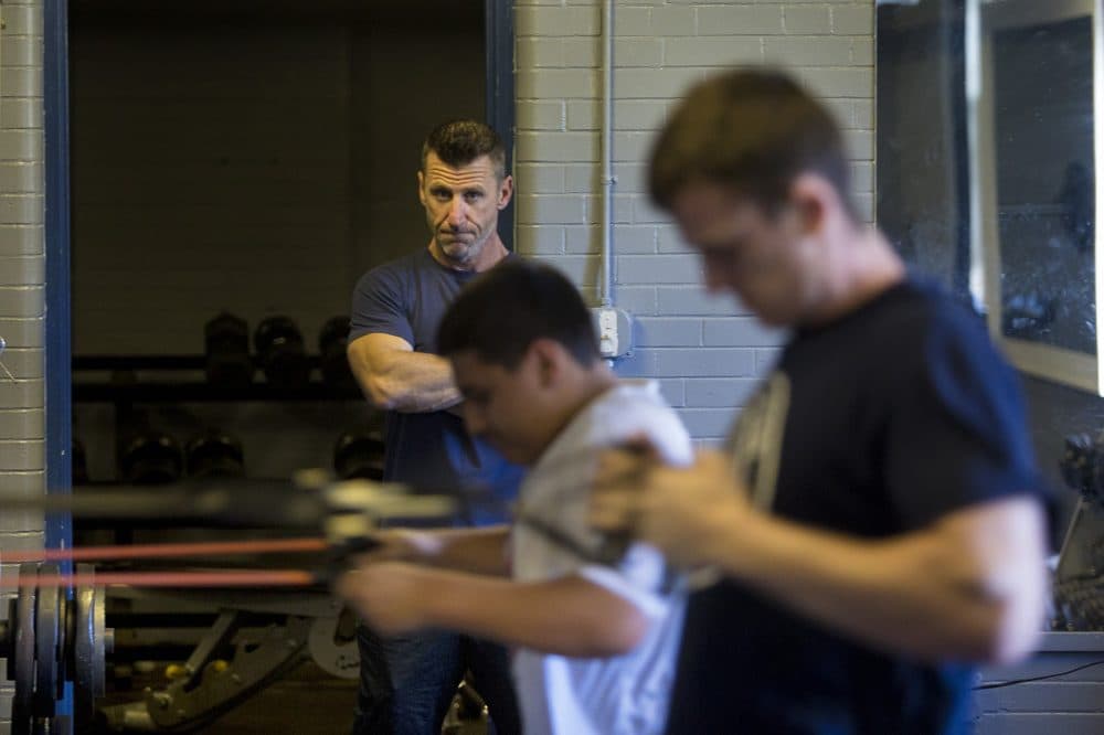 Marine veteran Jeff Buckley keeps an eye on workout participants doing band pulls in the basement of the All Dorchester Leadership Program at Town Field. (Jesse Costa/WBUR)