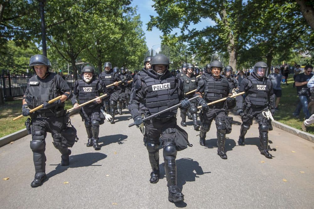 Tactical police in full riot gear walk in formation down a path in the Boston Common towards Boylston Street. (Jesse Costa/WBUR)