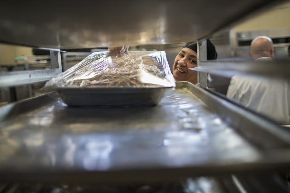Eberidy Velazquez places a wrapped pan of turkey meat ready to be stored for Thanksgiving Day. (Jesse Costa/WBUR)