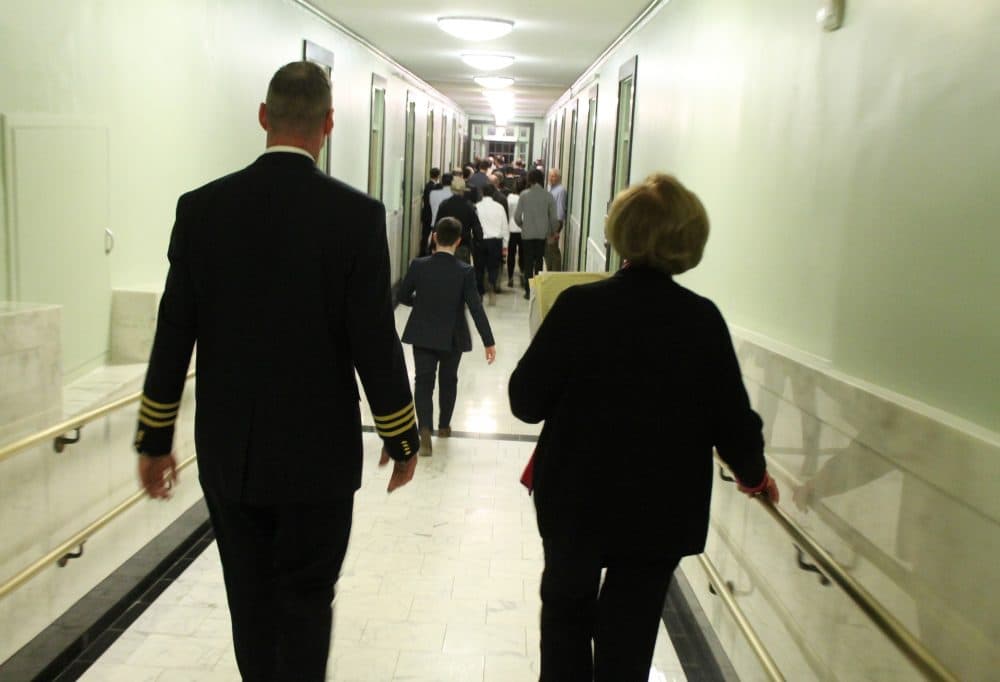 Chief Court Officer Paul Dooley walked Majority Leader Harriette Chandler toward the Gardner Auditorium where her colleagues elected her acting Senate president. (Sam Doran/SHNS)