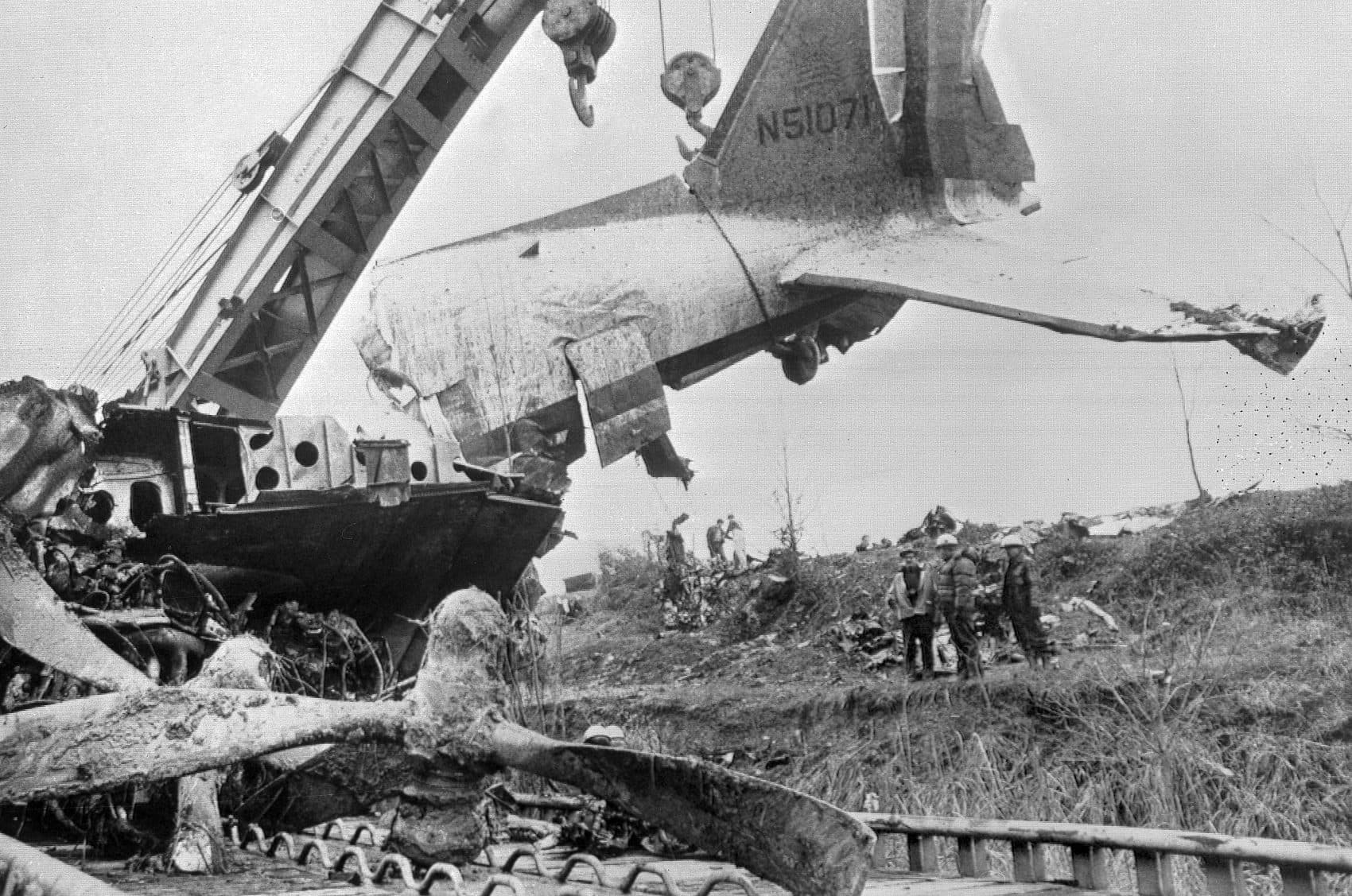 Workers watch as a large crane swings the tail seciton of the wrecked DC-3 on to a flatbed car as the remains of the plane are cleared away at Dress Regional Airport in Evansville, Ind., Dec. 16, 1977. (Chuck Robinson/AP)
