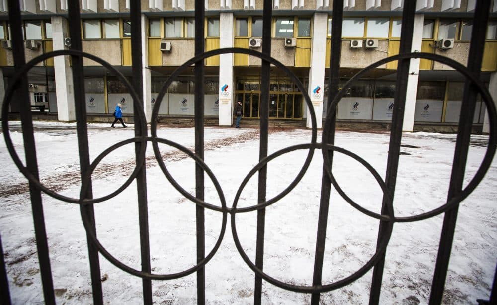 People walk at the building of the Russian Olympic Committee is seen through a gate decorated with the Olympic rings in Moscow, Russia, Wednesday, Dec. 6, 2017. The International Olympic Committee has barred the Russian team from competing in Pyeongchang in February over widespread doping at the last edition of the Winter Games in 2014. (Alexander Zemlianichenko/AP)