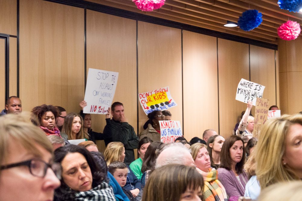 Parents hold signs protesting new start times at Boston Public Schools. (Max Larkin/WBUR)
