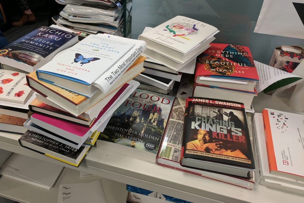 A pile of books sits in On Point's Boston offices. (Brian Amaral/WBUR)