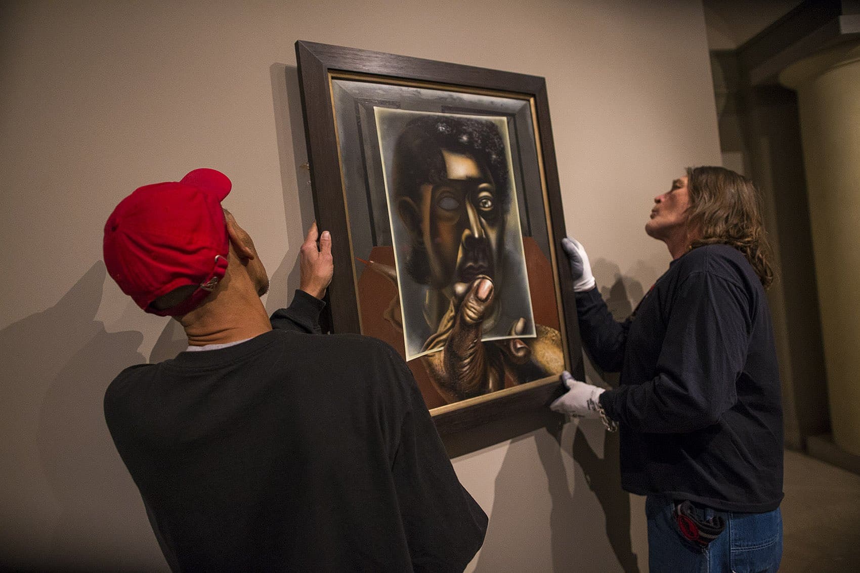 Museum of Fine Arts facilities workers Bryan Campbell and Paul Picardi install “Autorretrato con Espejo (Self-Portrait with Mirror)” by David Alfaro Siqueiros. (Jesse Costa/WBUR)